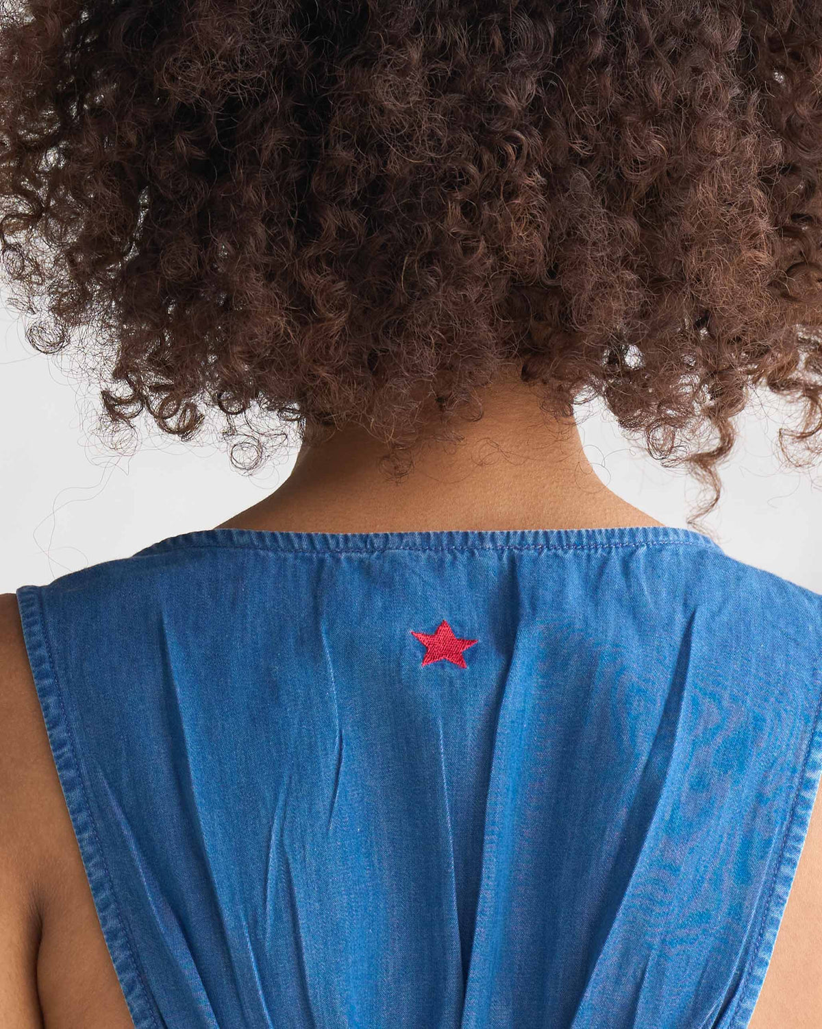 Close-up of a red star embroidered on the upper back of a blue short racerback dress.