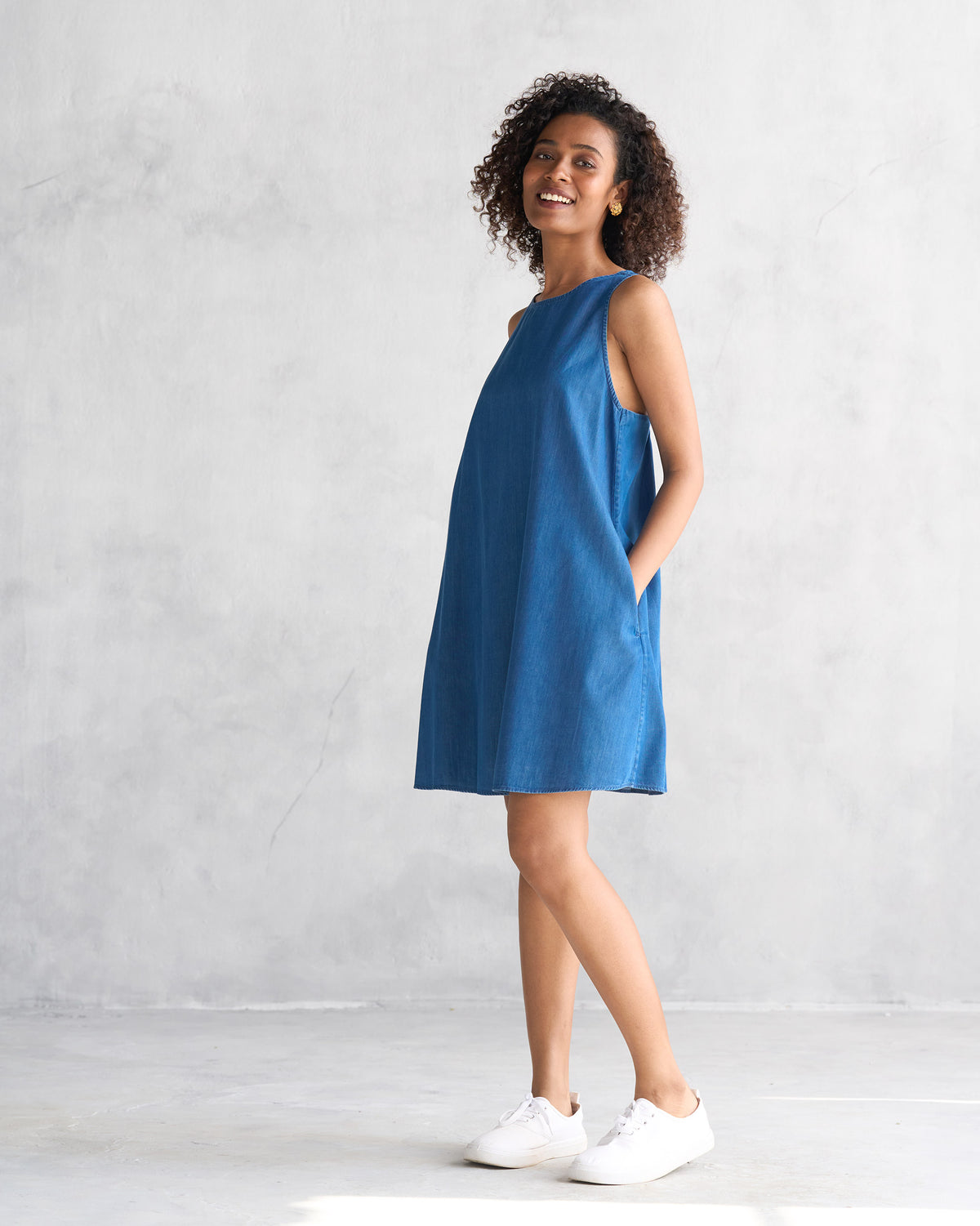 Side view of a blue short racerback dress with side pockets.