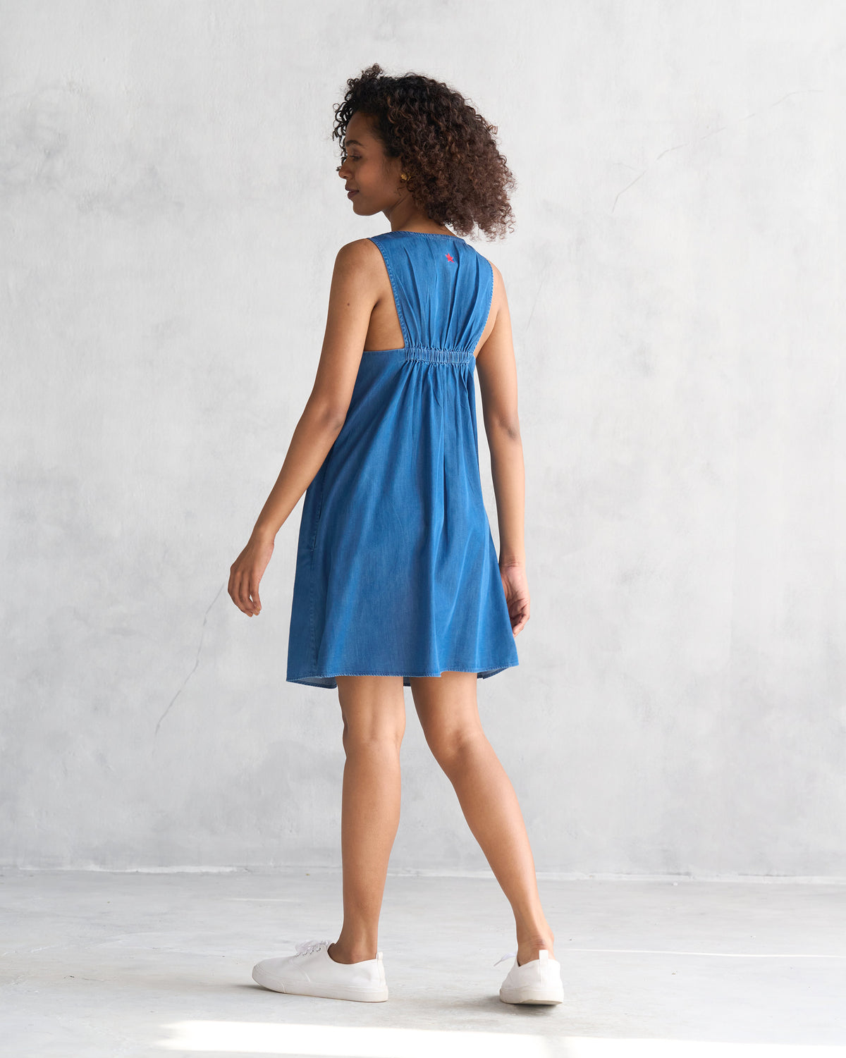 Back of a blue short racerback dress worn by a person.