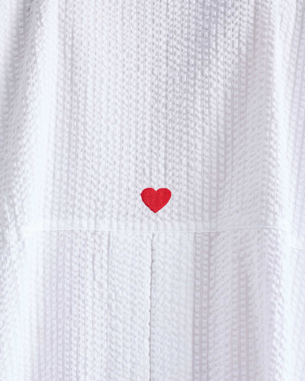 Close-up of a red embroidered heart on white Cirrus seersucker.