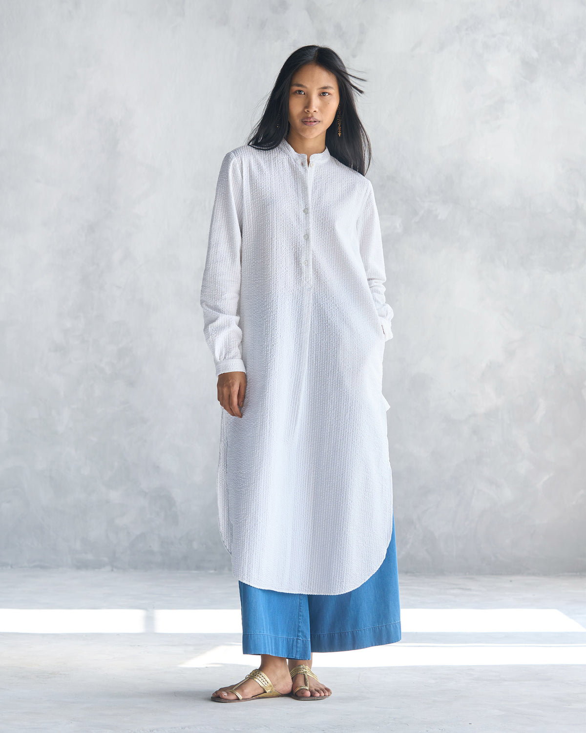 Person wearing a white seersucker long kurta with side slits.
