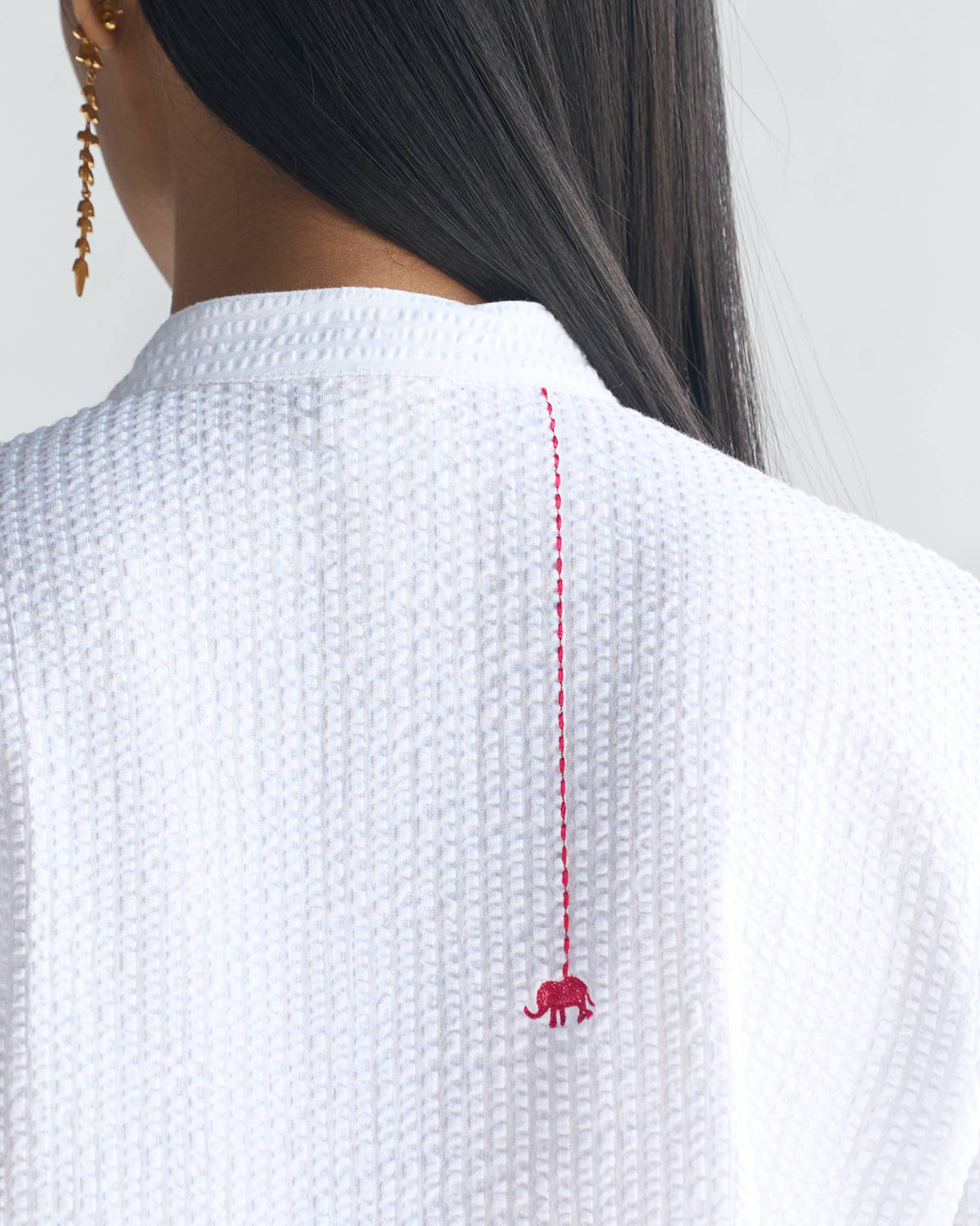 Close-up of the back of a white seersucker kurta with a red elephant motif.
