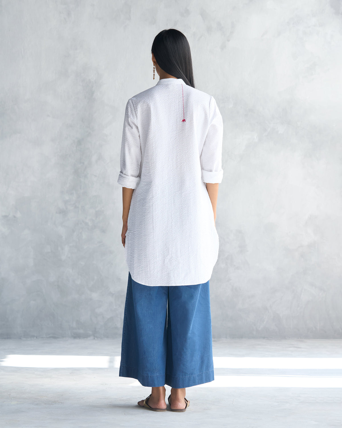 Back of a white seersucker mid-length kurta with a curved hem.