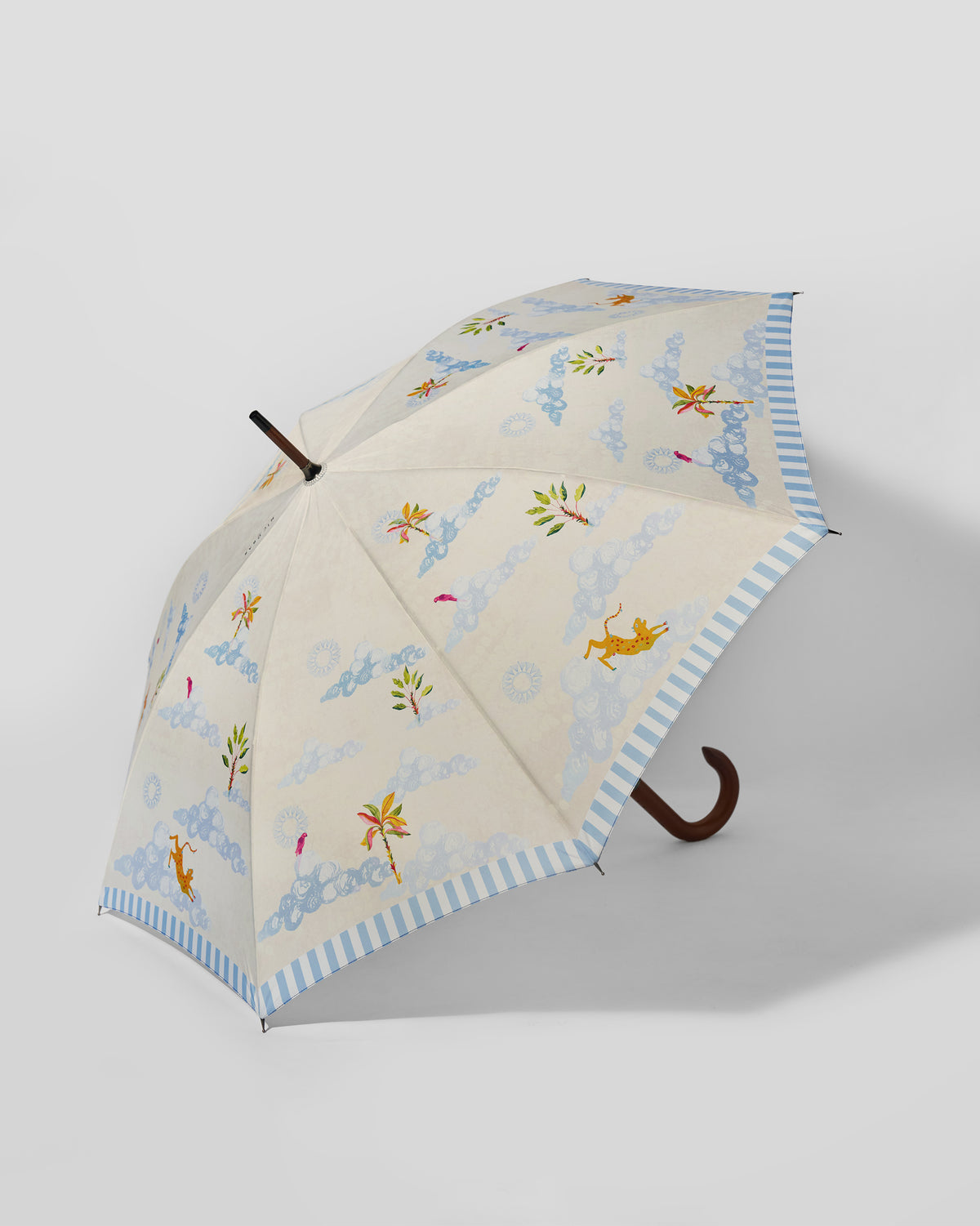 Zanzibar Umbrella open at an angle, with a cream canopy, blue stripe edge and palm motifs.