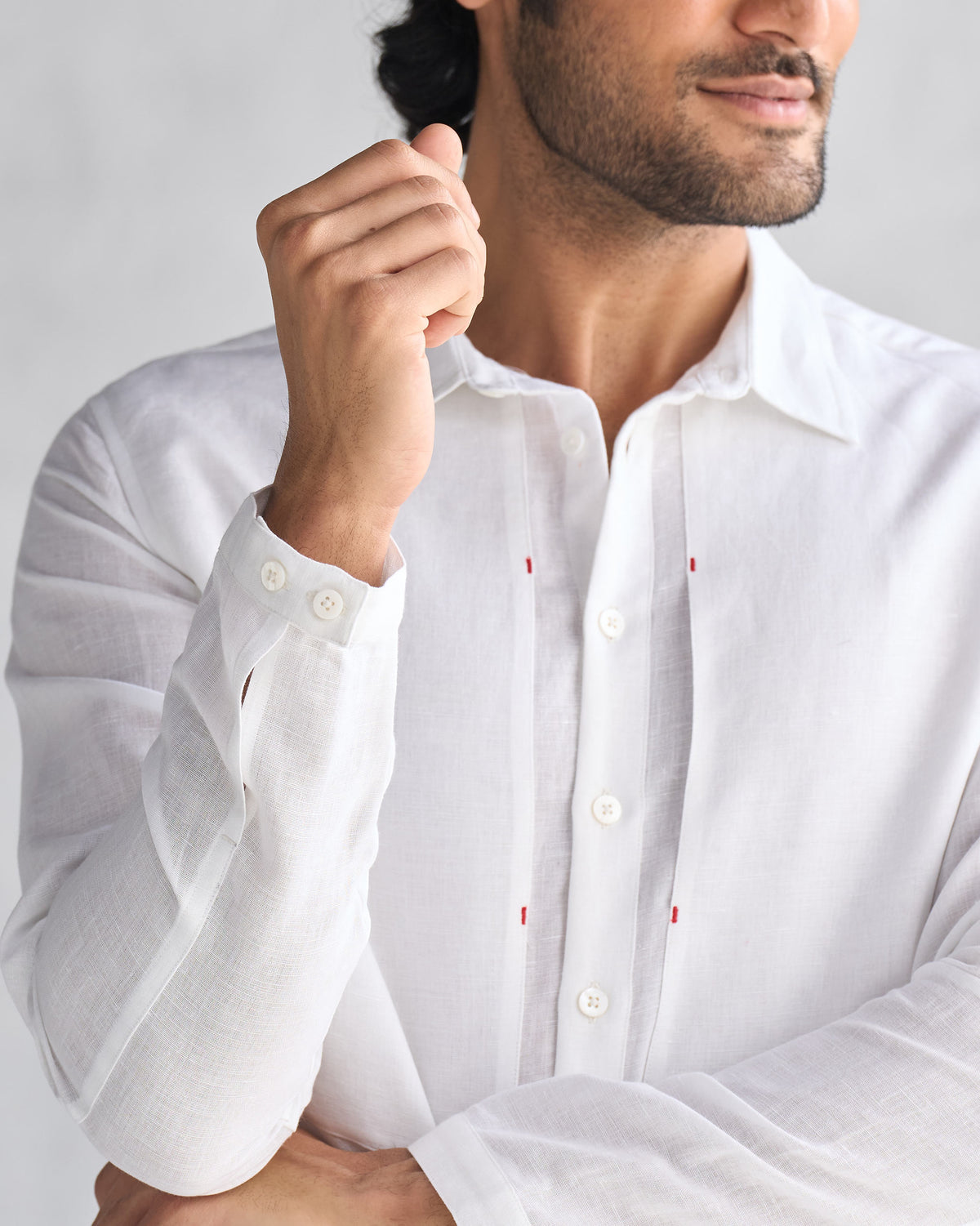 Close-up of a white August Shirt showing its cuff buttons and red placket stitching.