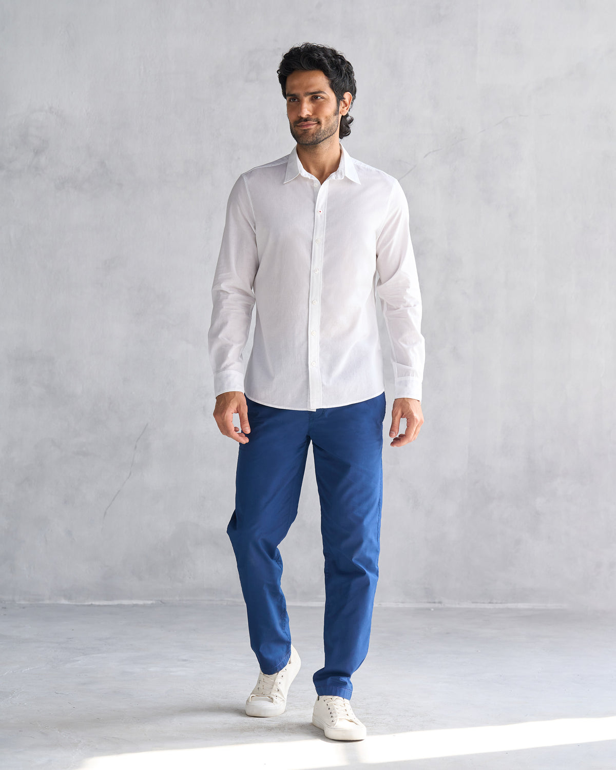 Person wearing a white Classic shirt untucked over blue trousers.