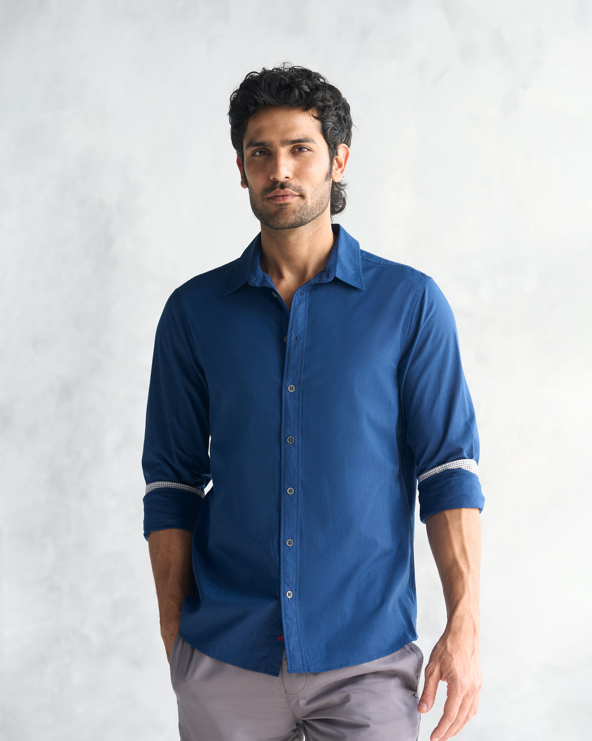 Person wearing a navy Classic Shirt with rolled sleeves and a pointed collar.