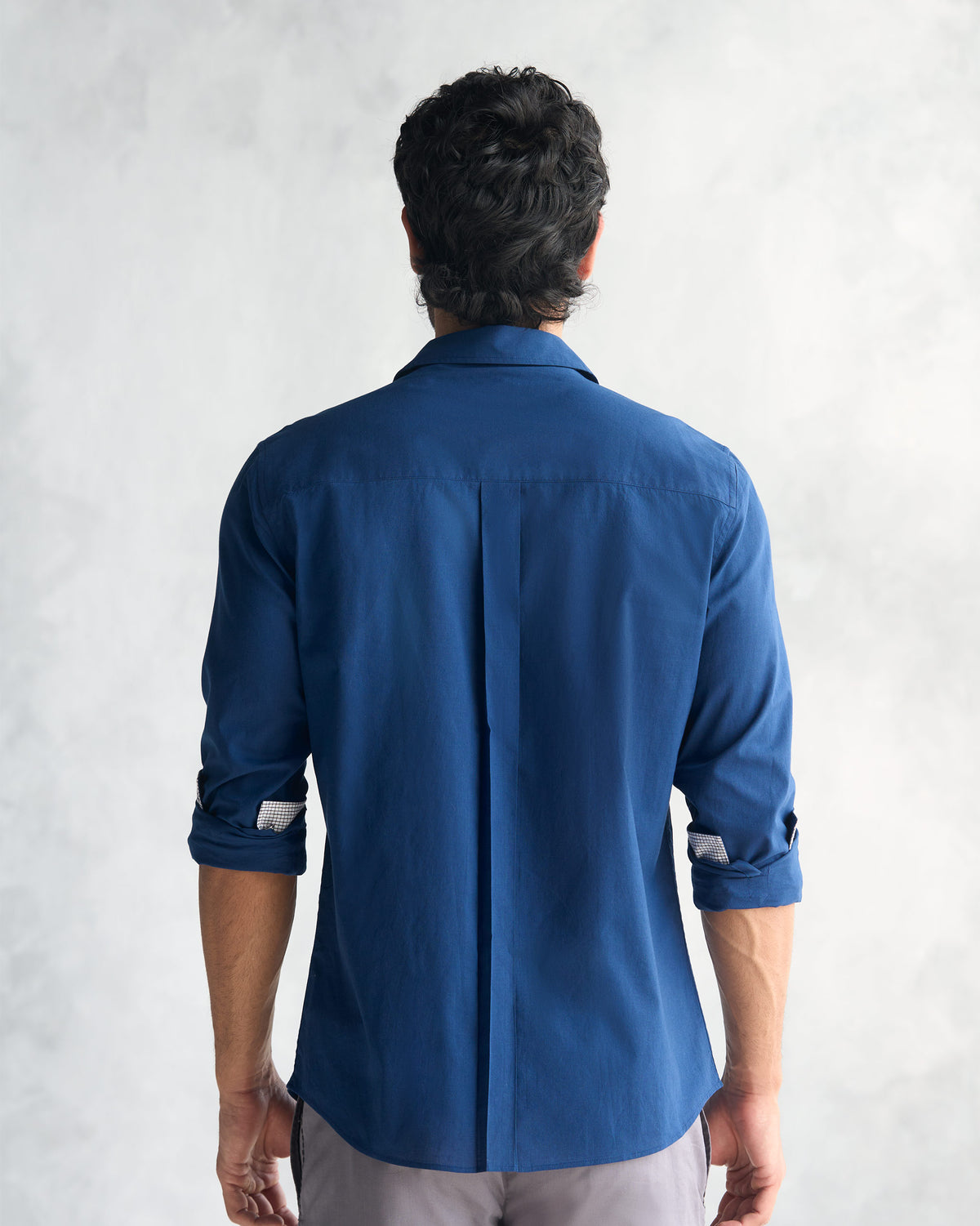 Back of a navy Classic Shirt showing the yoke and center box pleat.
