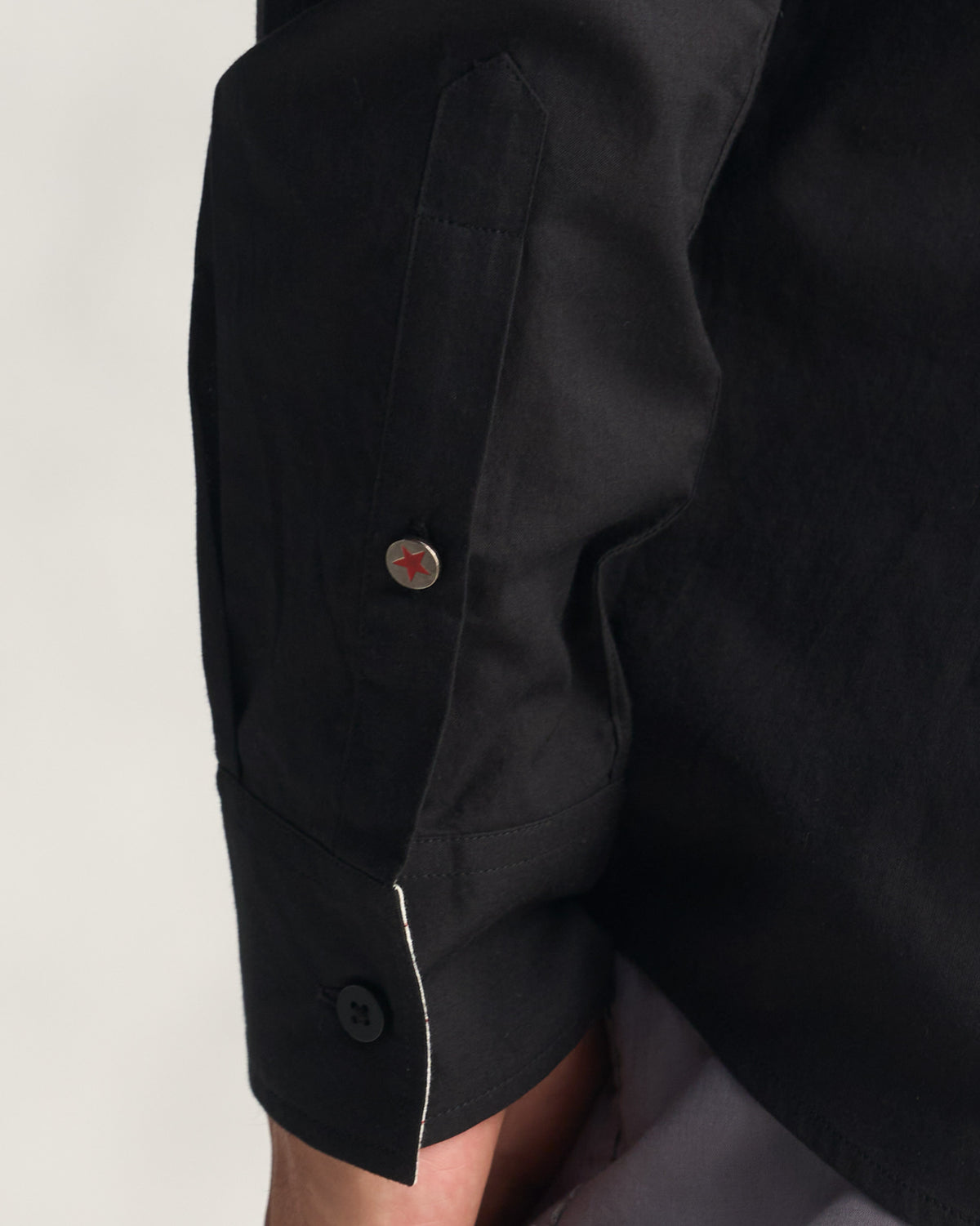 Close-up of black shirt cuff with a silver red-star button.