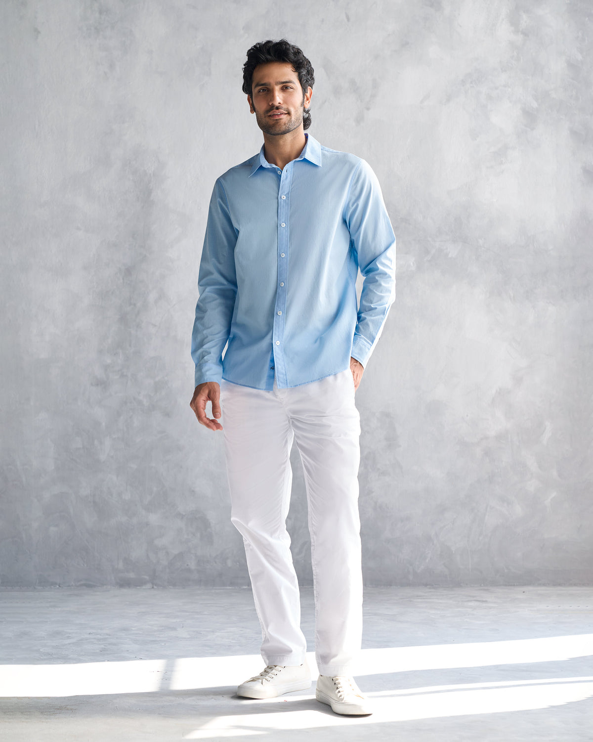 Person wearing a light blue classic shirt untucked.