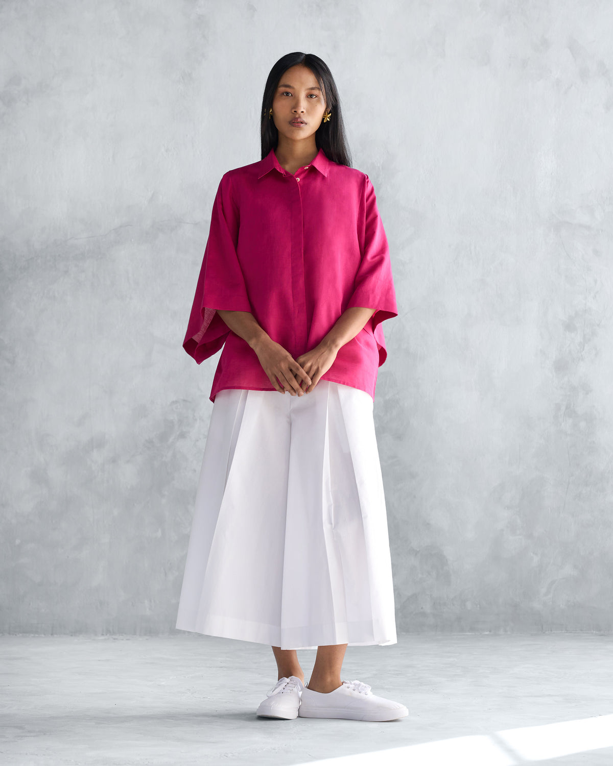 Person wearing a berry Drop Armhole Shirt with wide sleeves over white pants.
