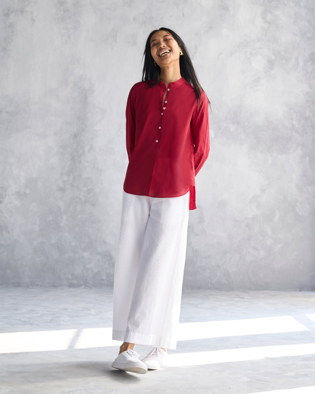Person wearing white seersucker Basic Pyjamas with a deep red tunic.
