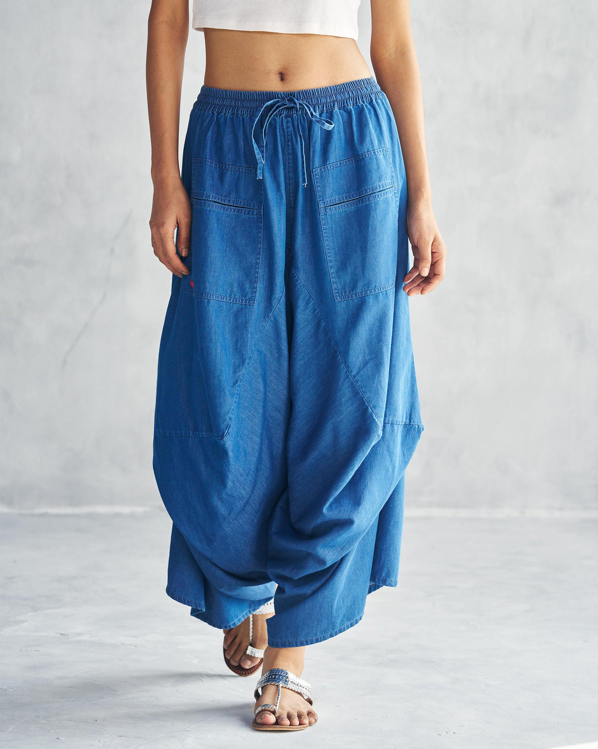 Person wearing blue Yoka Trousers with a drawstring waist and patch pockets.