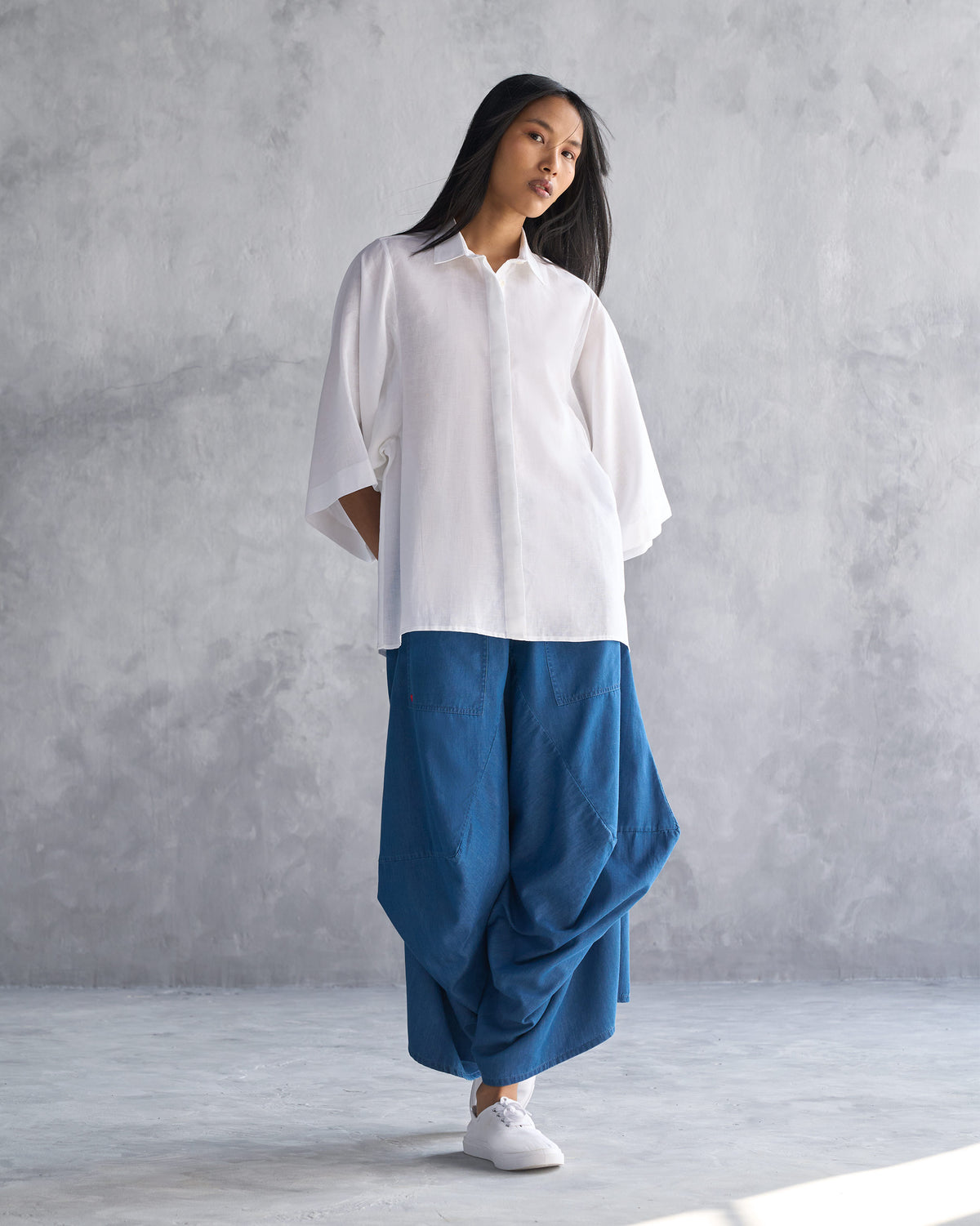 Person wearing blue Yoka Trousers with a wide, draped leg.