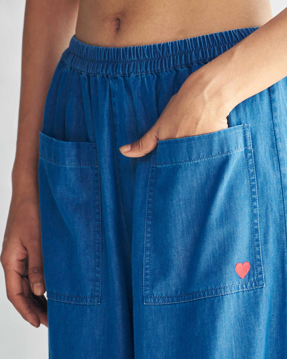 Close-up of blue Serene pants showing patch pockets with a red embroidered heart.