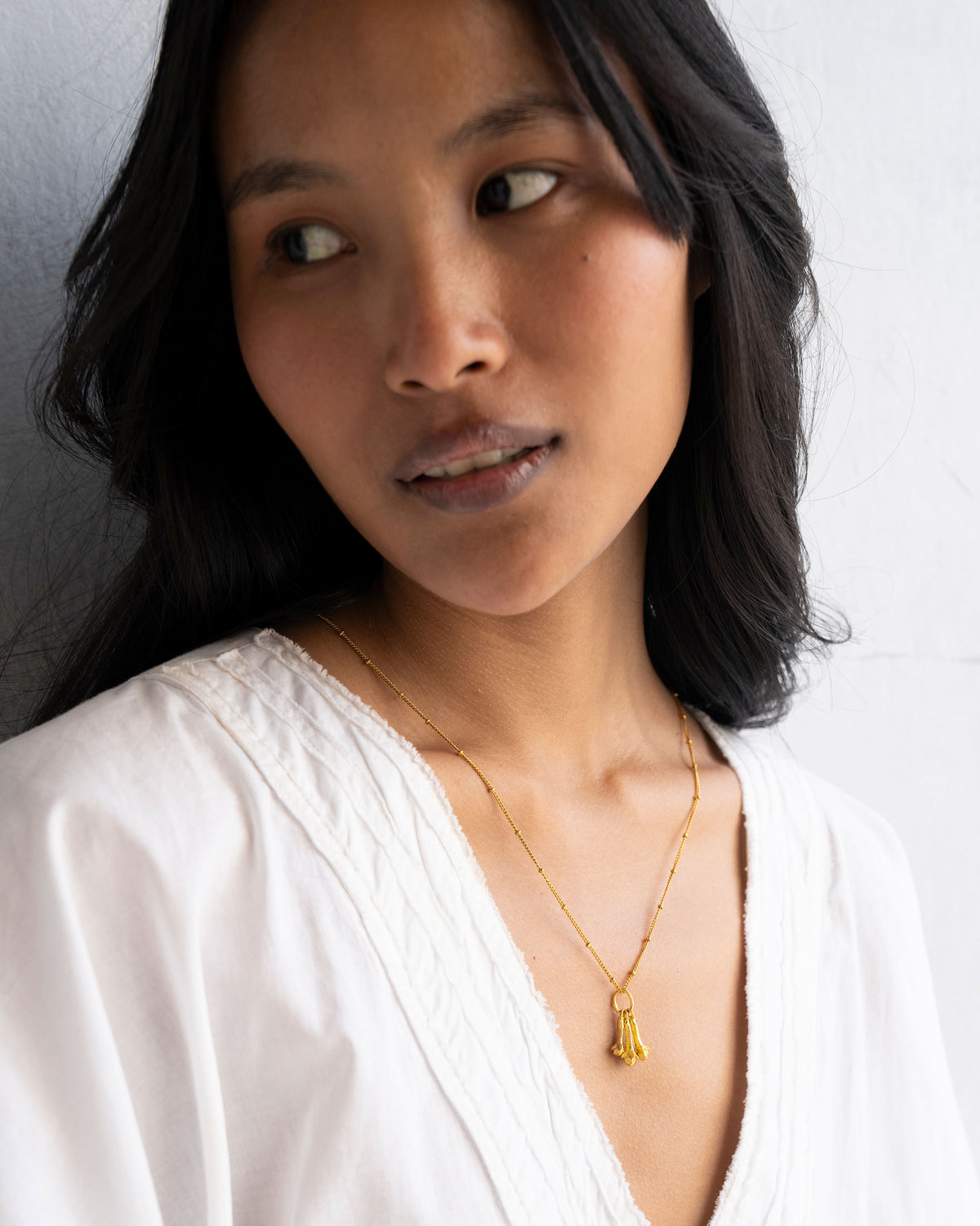 Set of three gold clove charms worn on a fine chain.