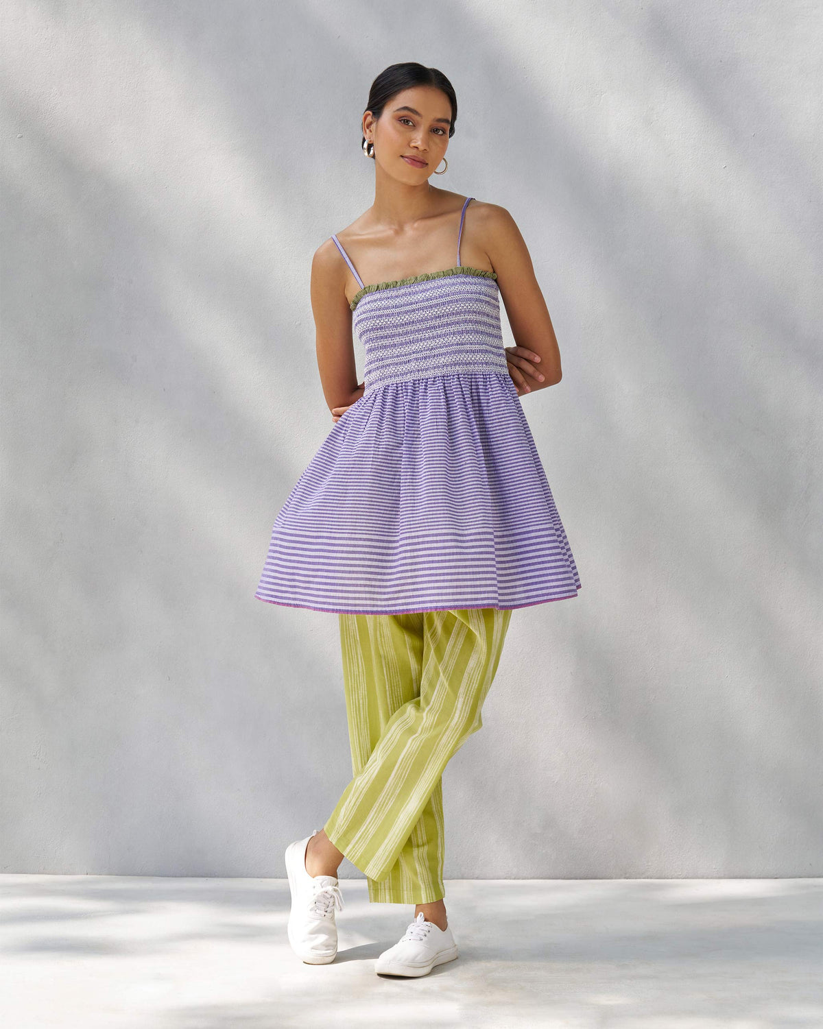 Person wearing a purple and white Paradise top with thin straps and a flared hem.