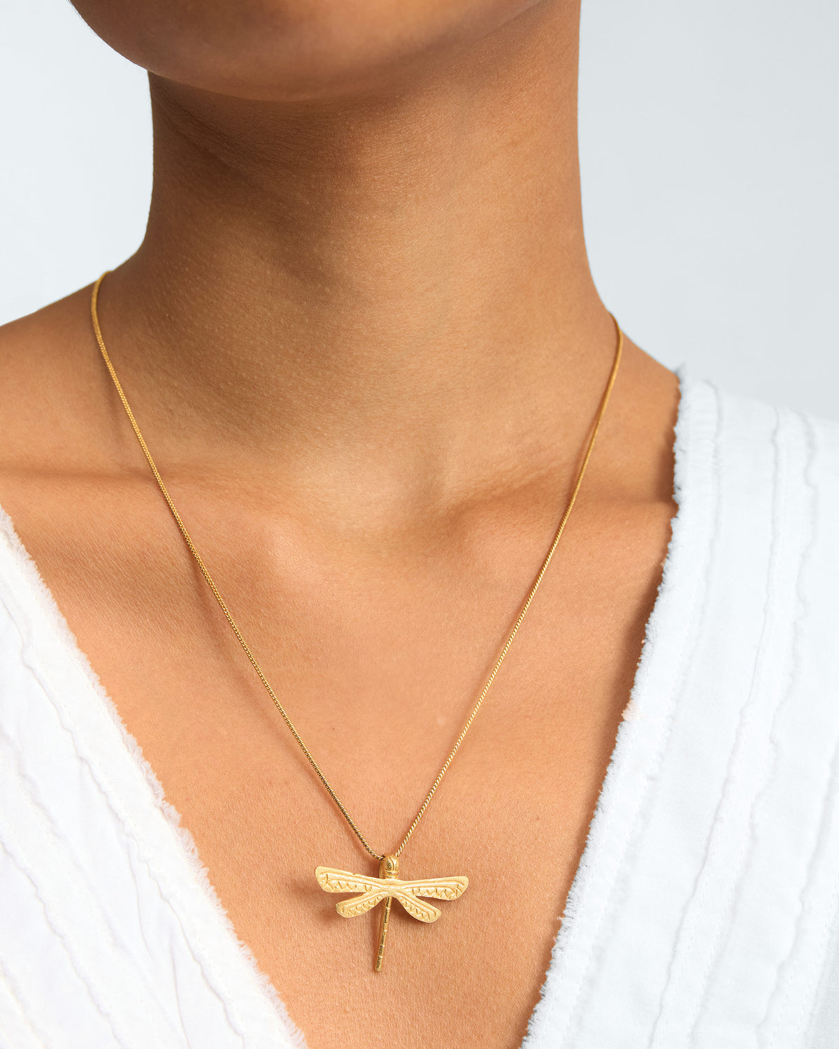 Person wearing a Dragonfly Charm pendant on a fine gold chain.