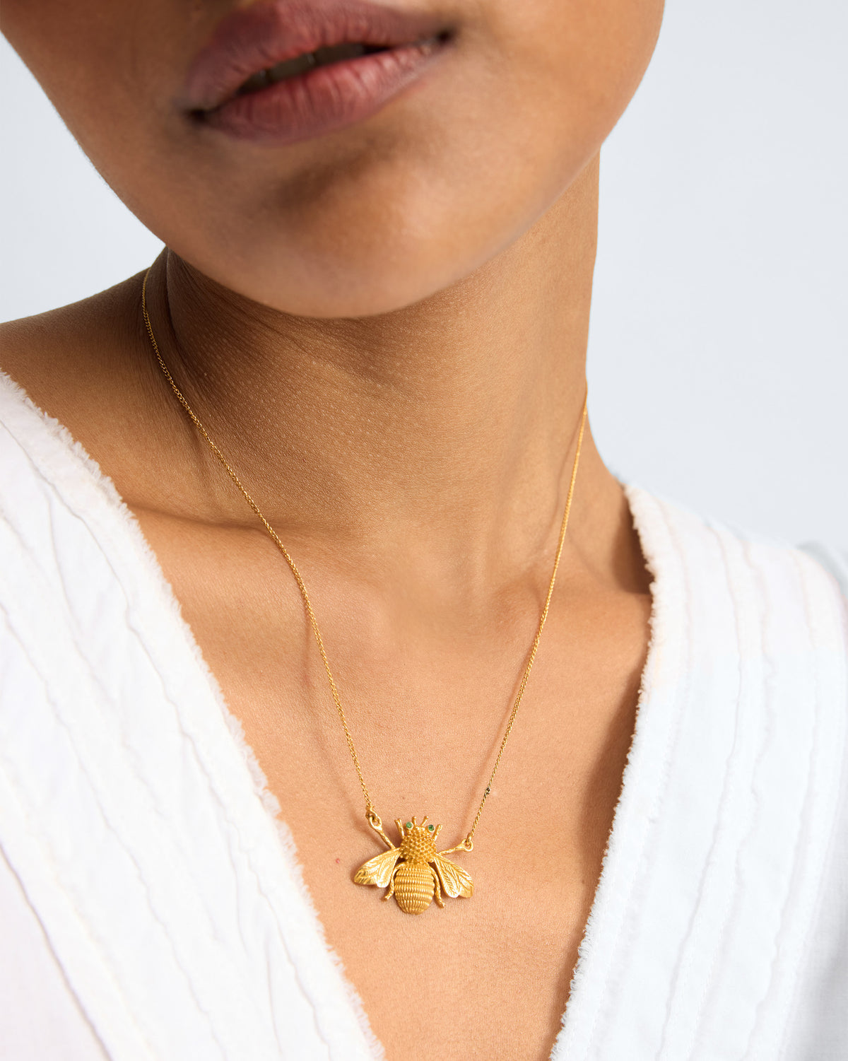 Person wearing Bee Necklace with a gold bee pendant centred on the chest.