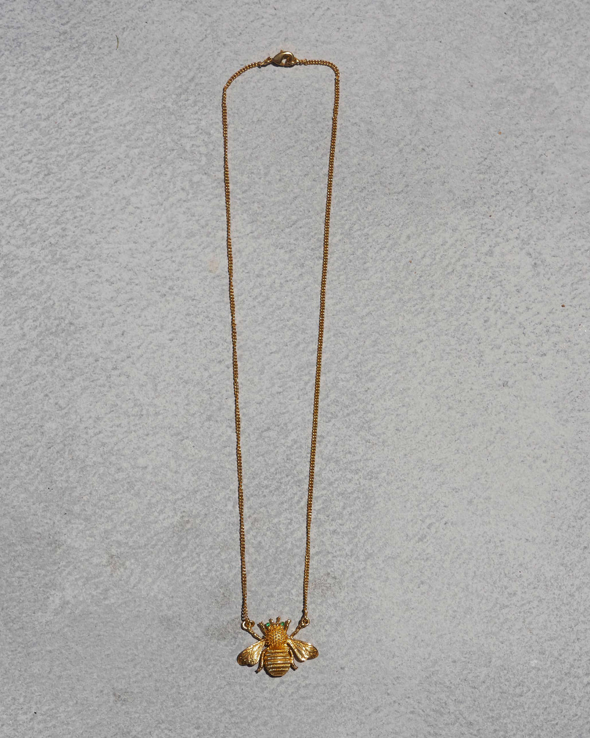 Bee Necklace laid flat, showing its gold bee pendant on a fine chain.