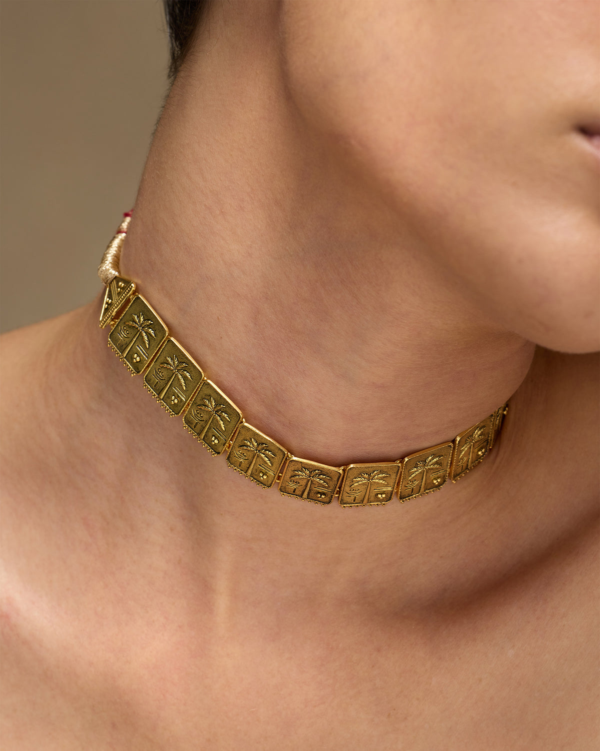 Antique gold coco palm necklace with embossed palm plaques at the neck.