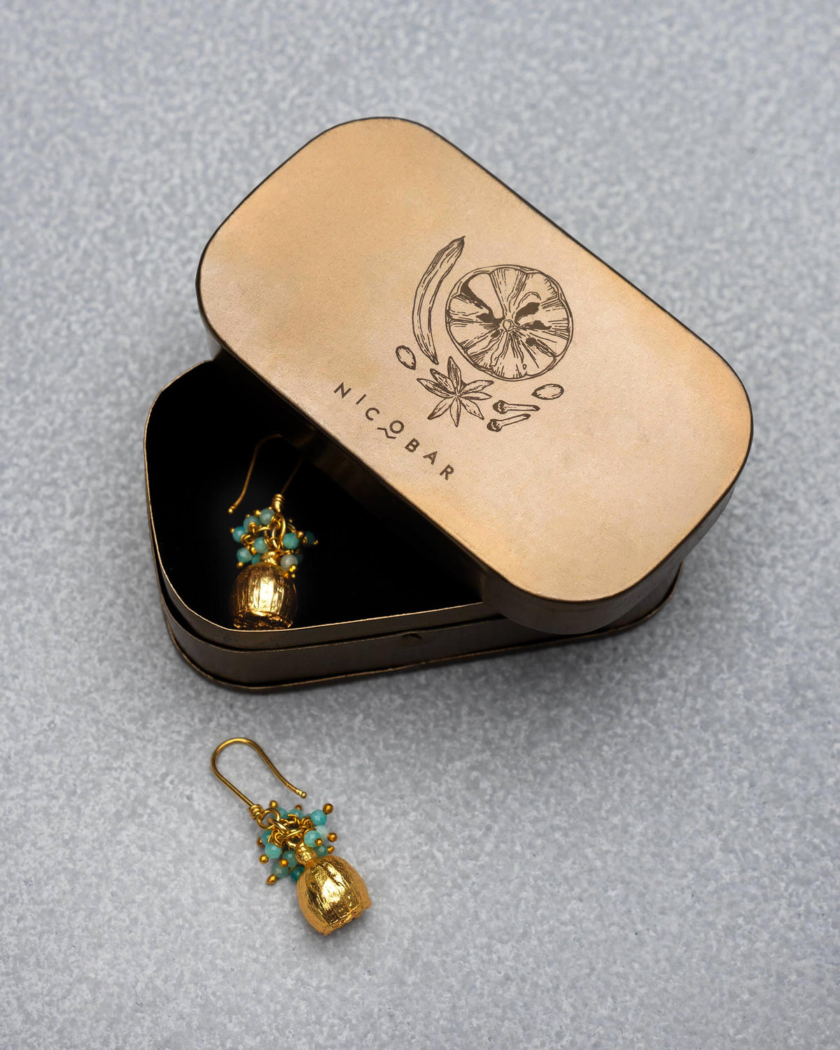 Pair of Himalayan Poppy Drops Earrings beside an open dark tin.