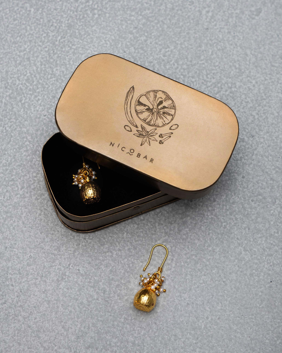 Gold Pearl Poppy Drop Earrings in an open tin with an illustrated lid.
