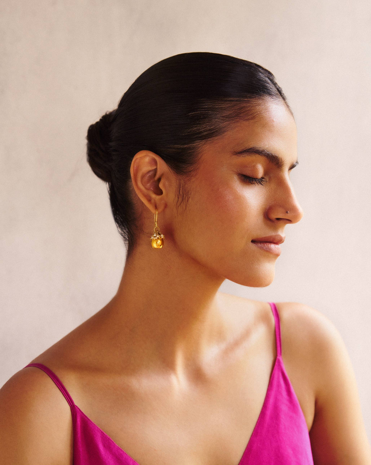 Side view of gold Pearl Poppy Drop Earrings worn on a person.