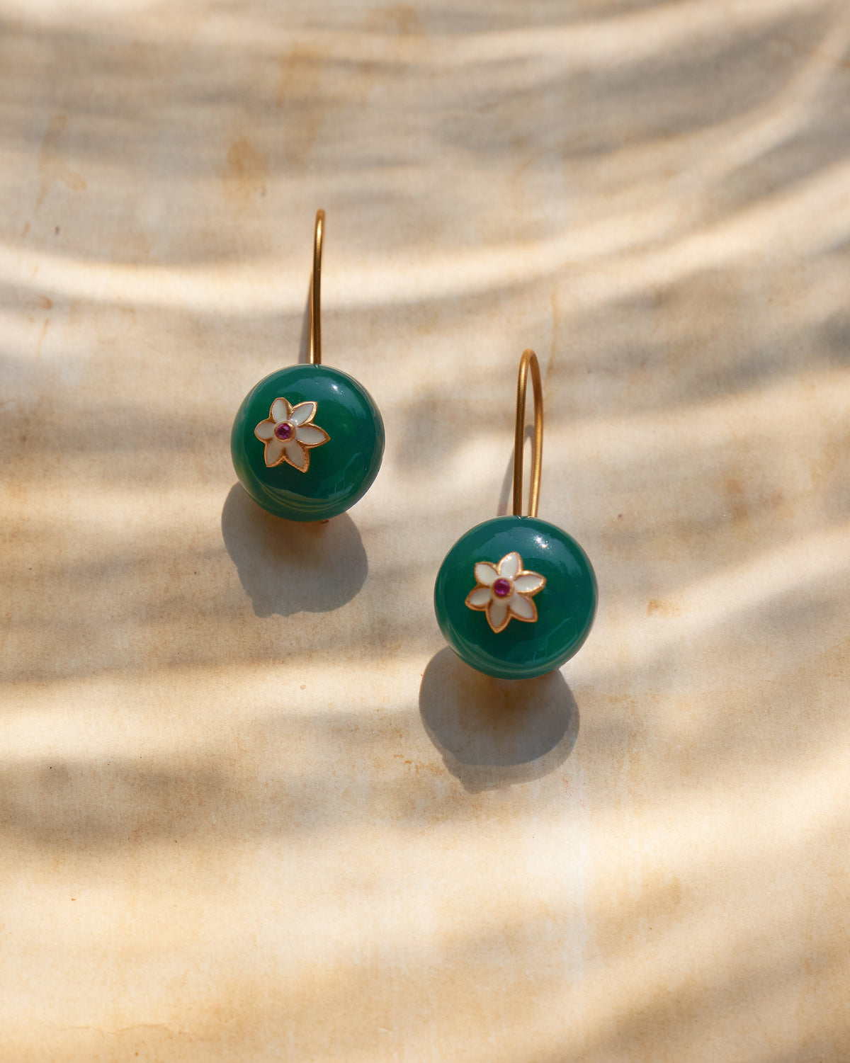 Pair of green onyx Aurora earrings with white flower and red centers.