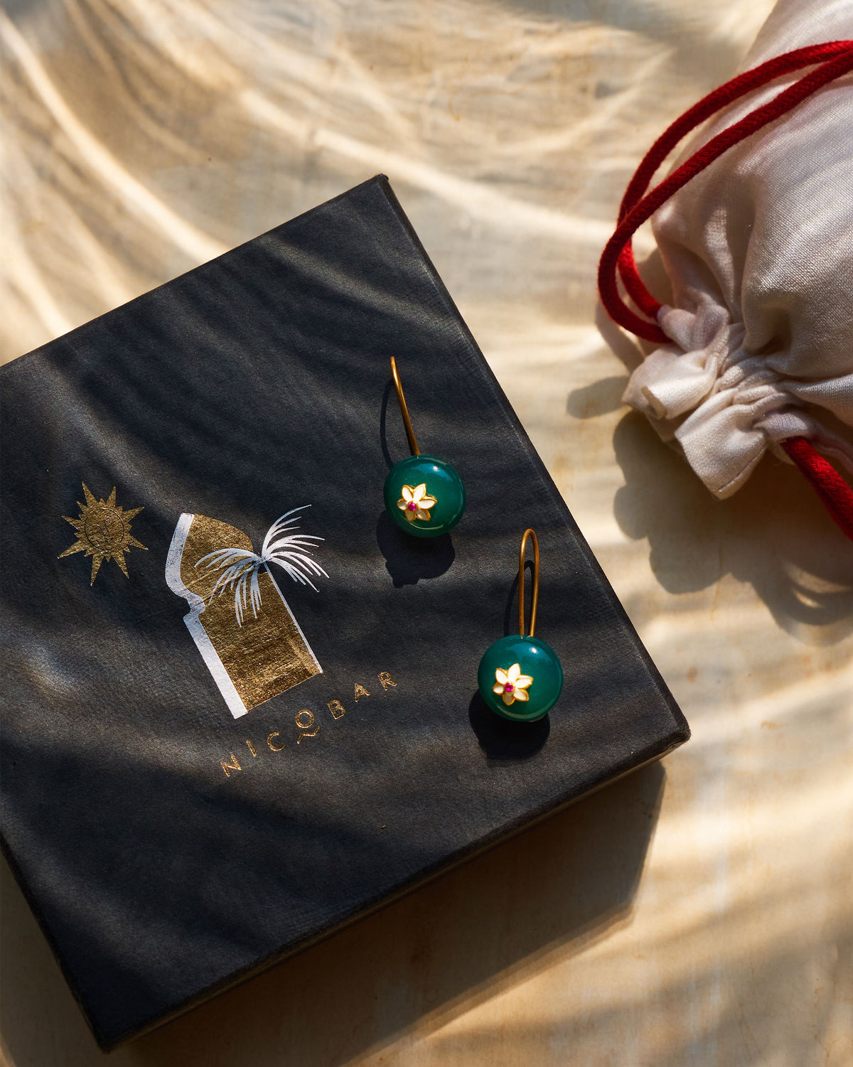 Green onyx Aurora earrings on a black Nicobar gift box.