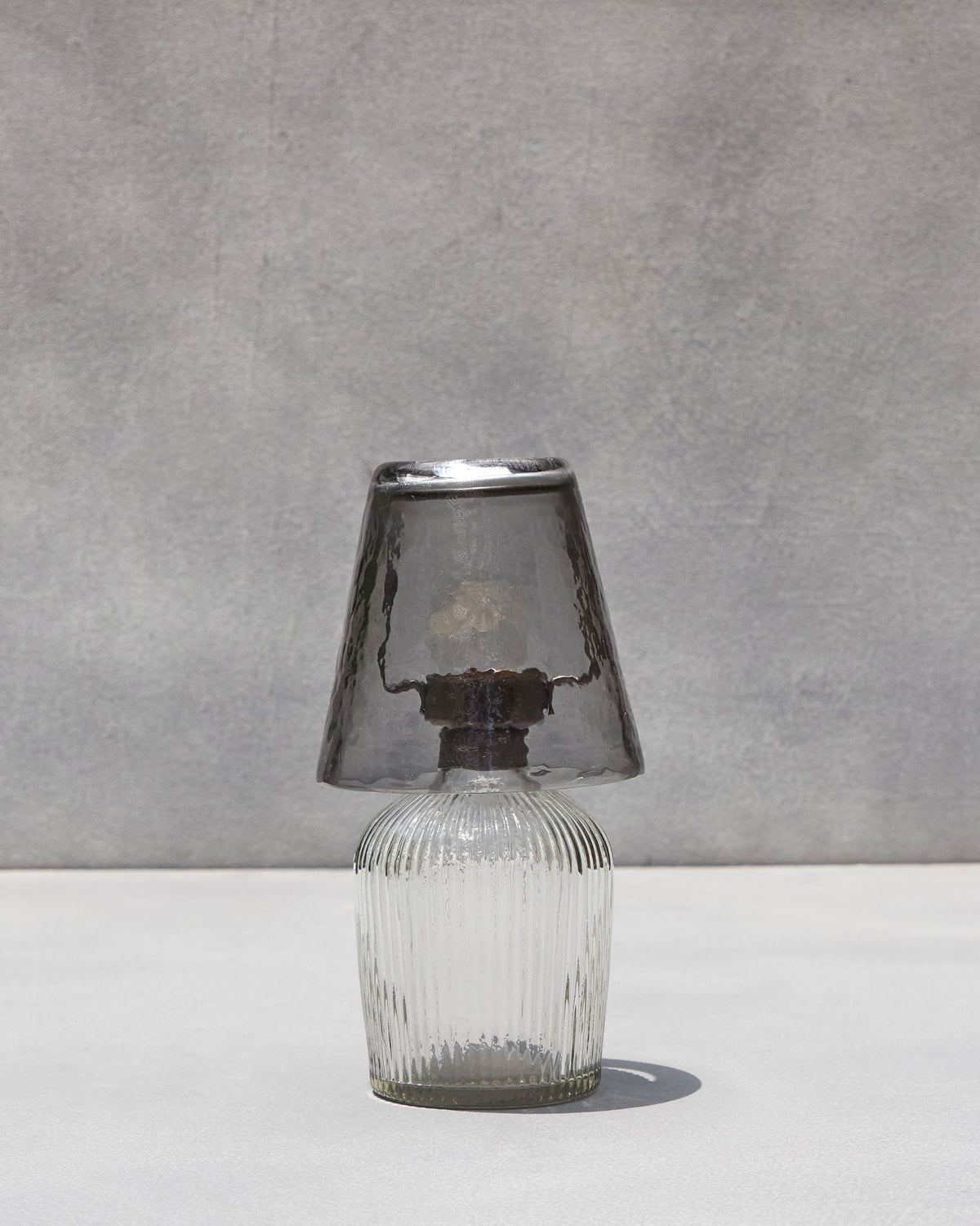 Asfar votive lamp with clear ribbed base and smoky grey conical shade.