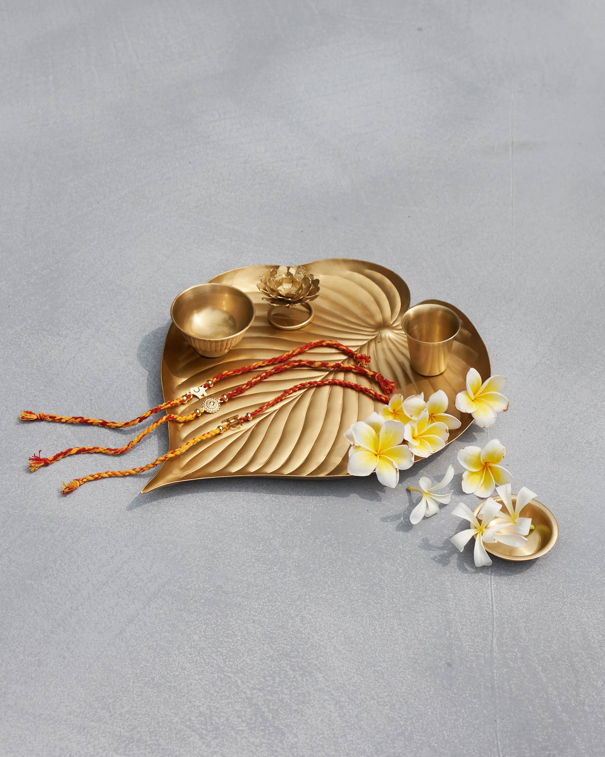 Asfar brass leaf tray styled with bowls, lotus holder, and flowers.