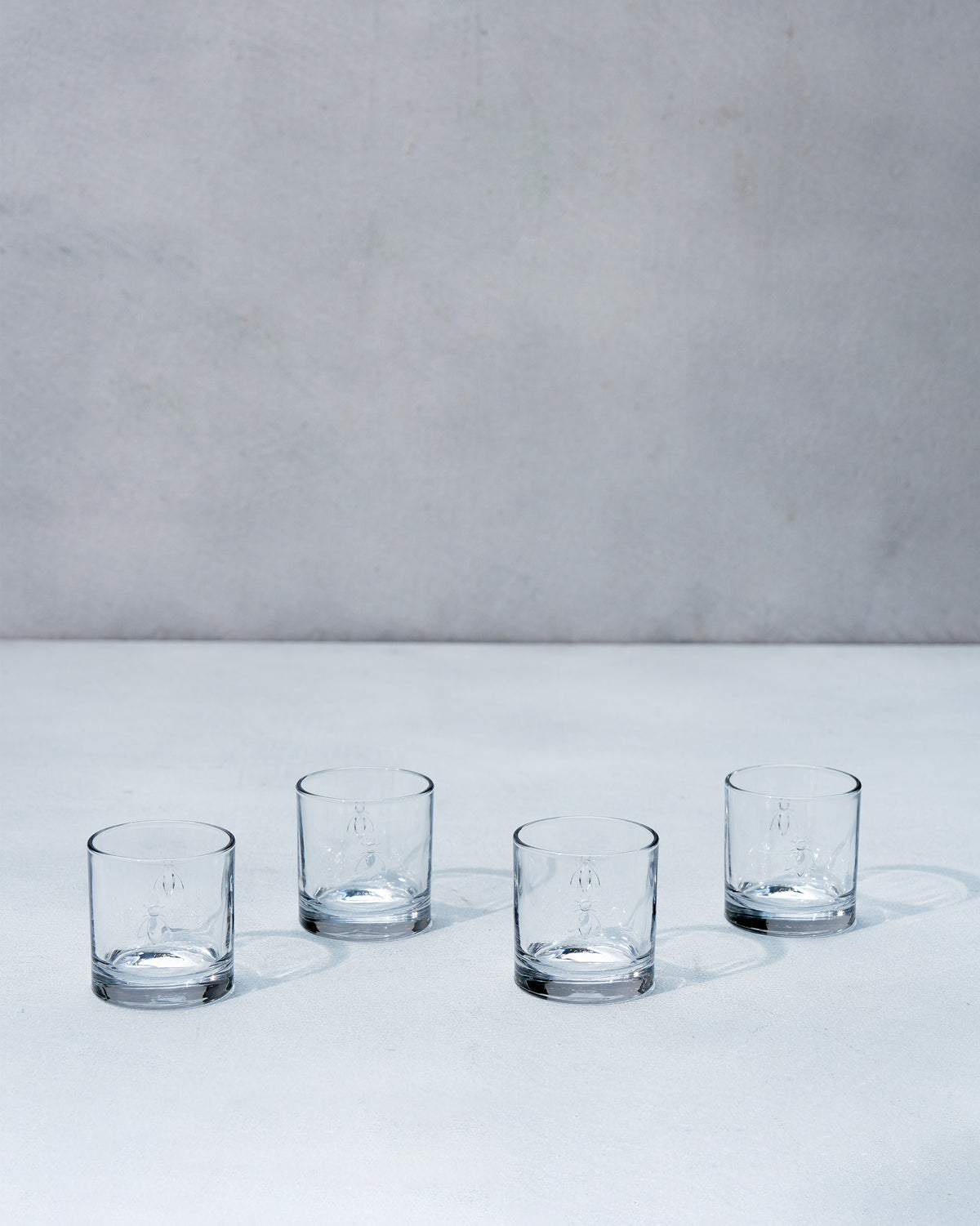 Four clear Bumble Bee whiskey glasses arranged in a row.
