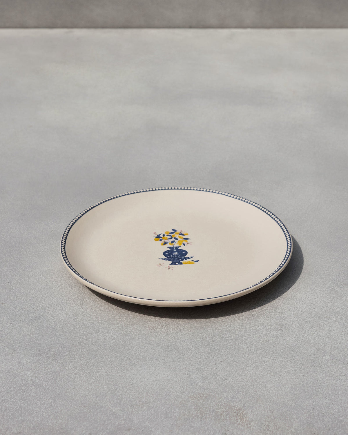 Sahara dinner plate with a blue vase of yellow lemons and a dotted blue rim.