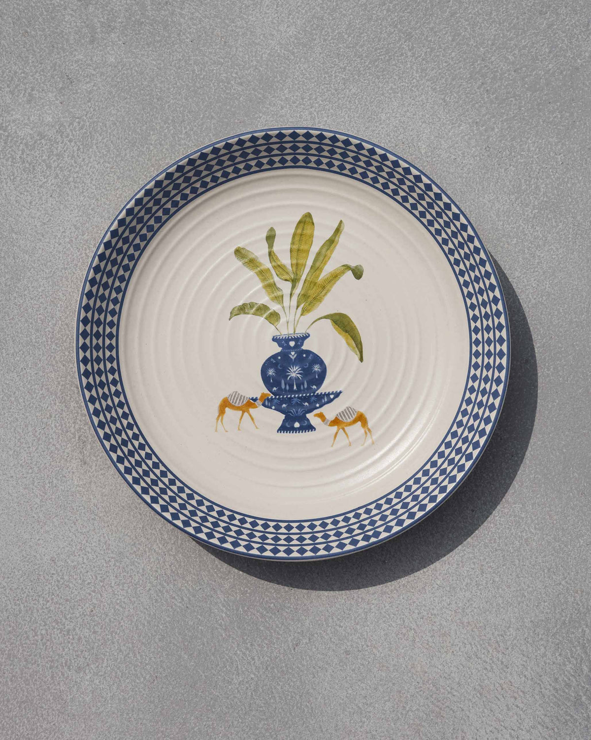 Sahara pasta plate with a blue vase, green plant and two orange animals.