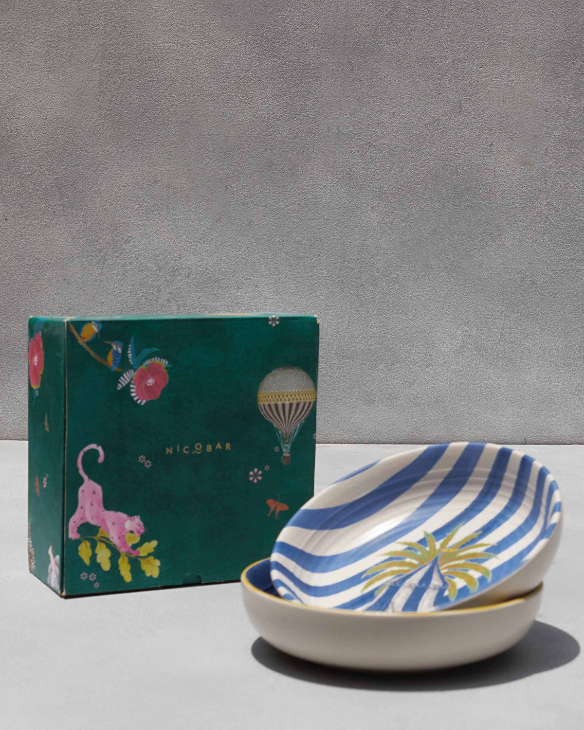 Sahara shallow bowls stacked beside their green Nicobar gift box.