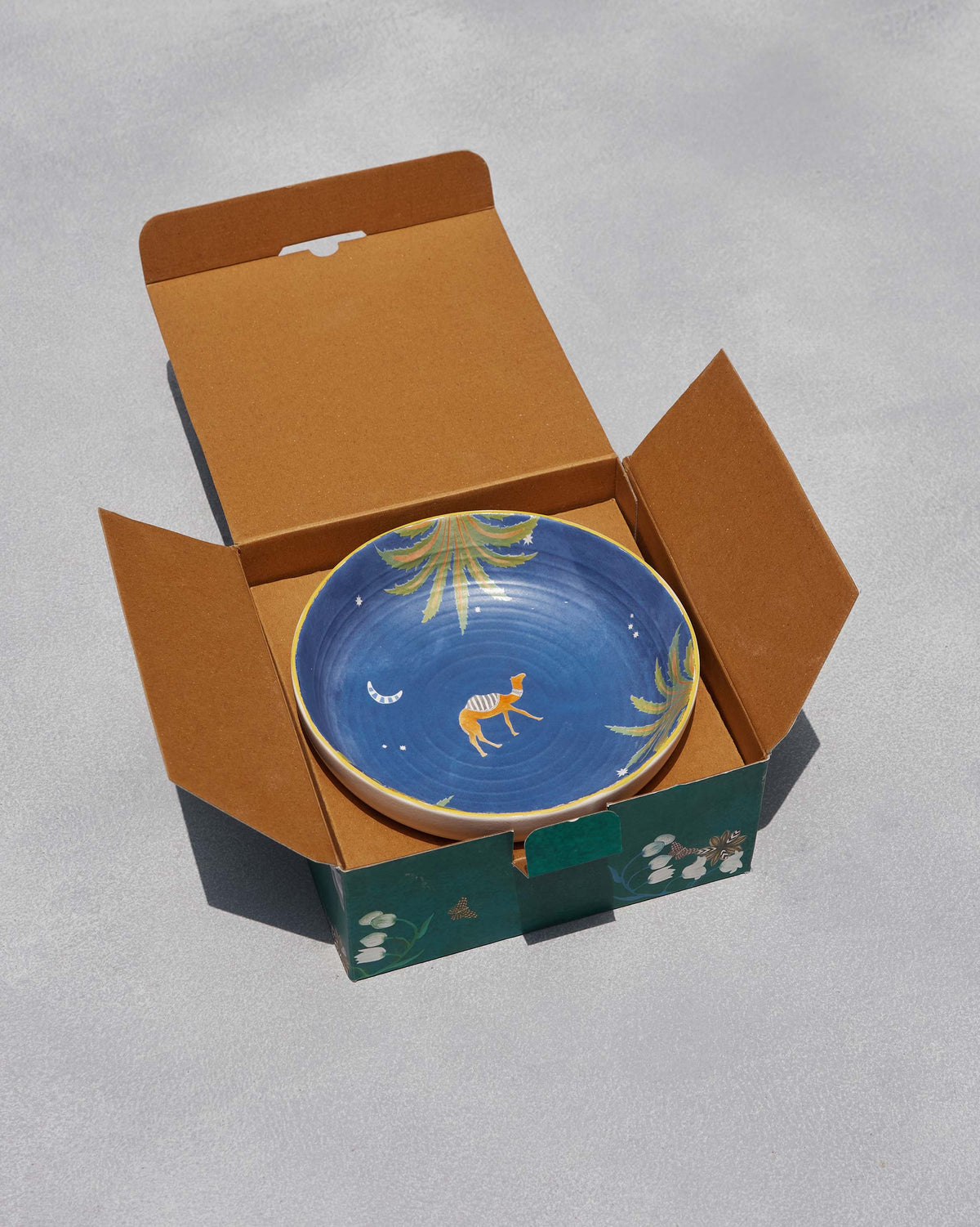 Sahara shallow bowl with camel motif nestled in its open gift box.