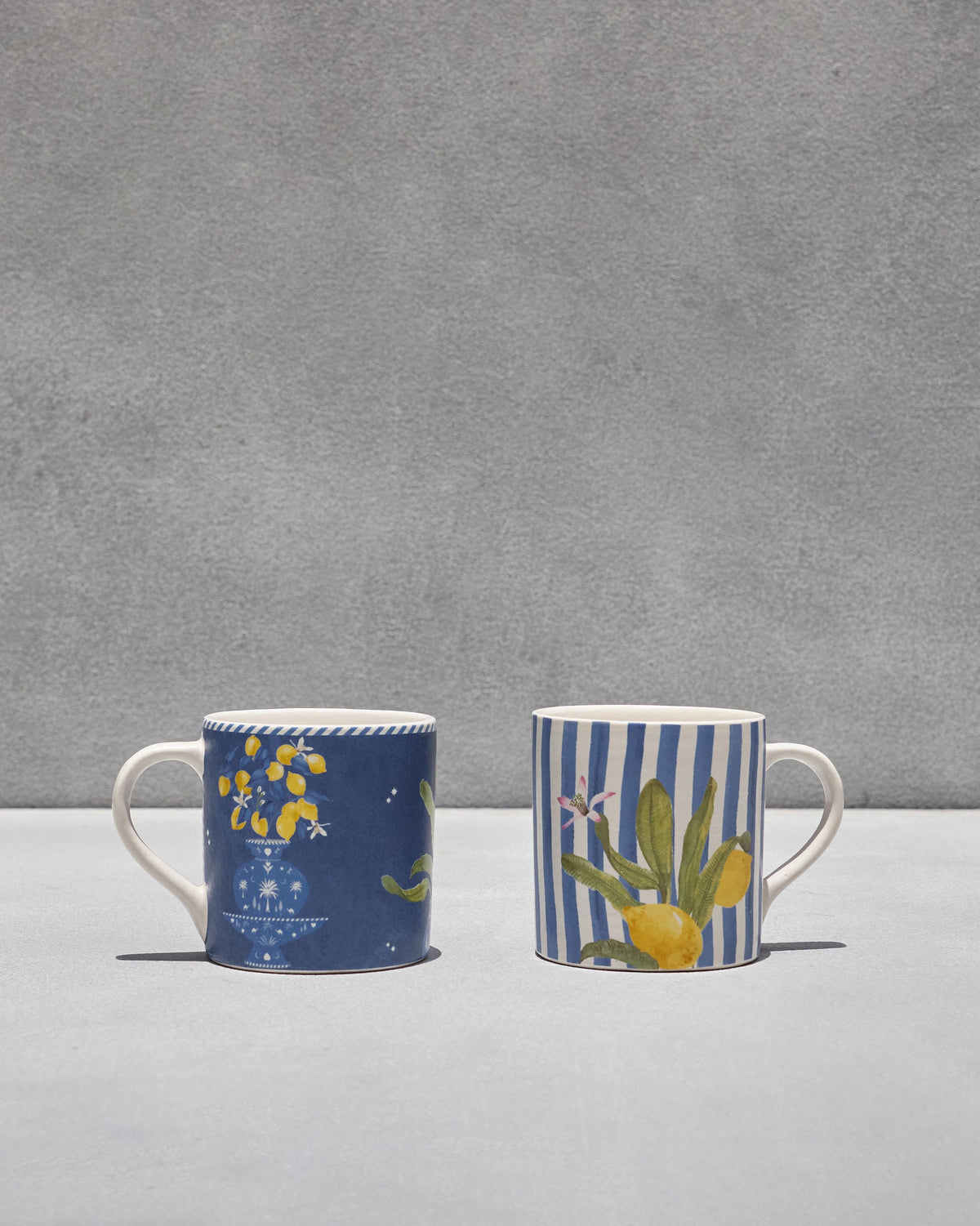 Pair of Asfar mugs: navy lemon urn design and blue-striped lemon branch design.