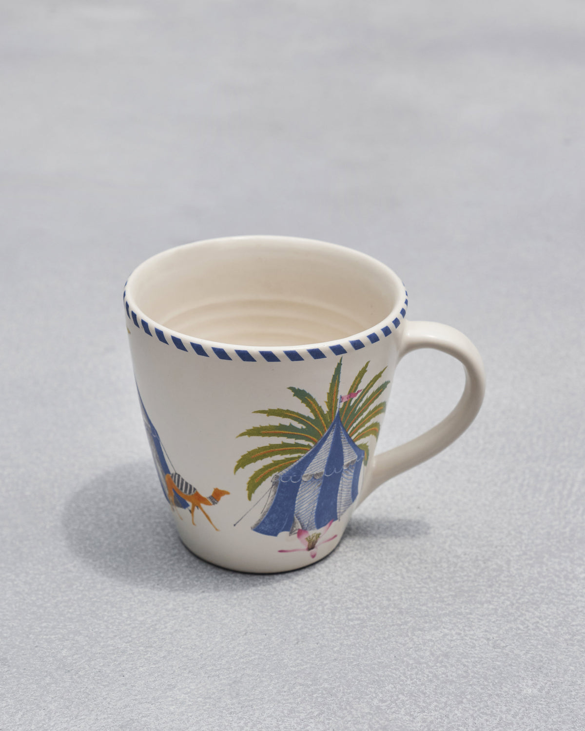 Sahara conical mug with a painted blue tent and palm tree.