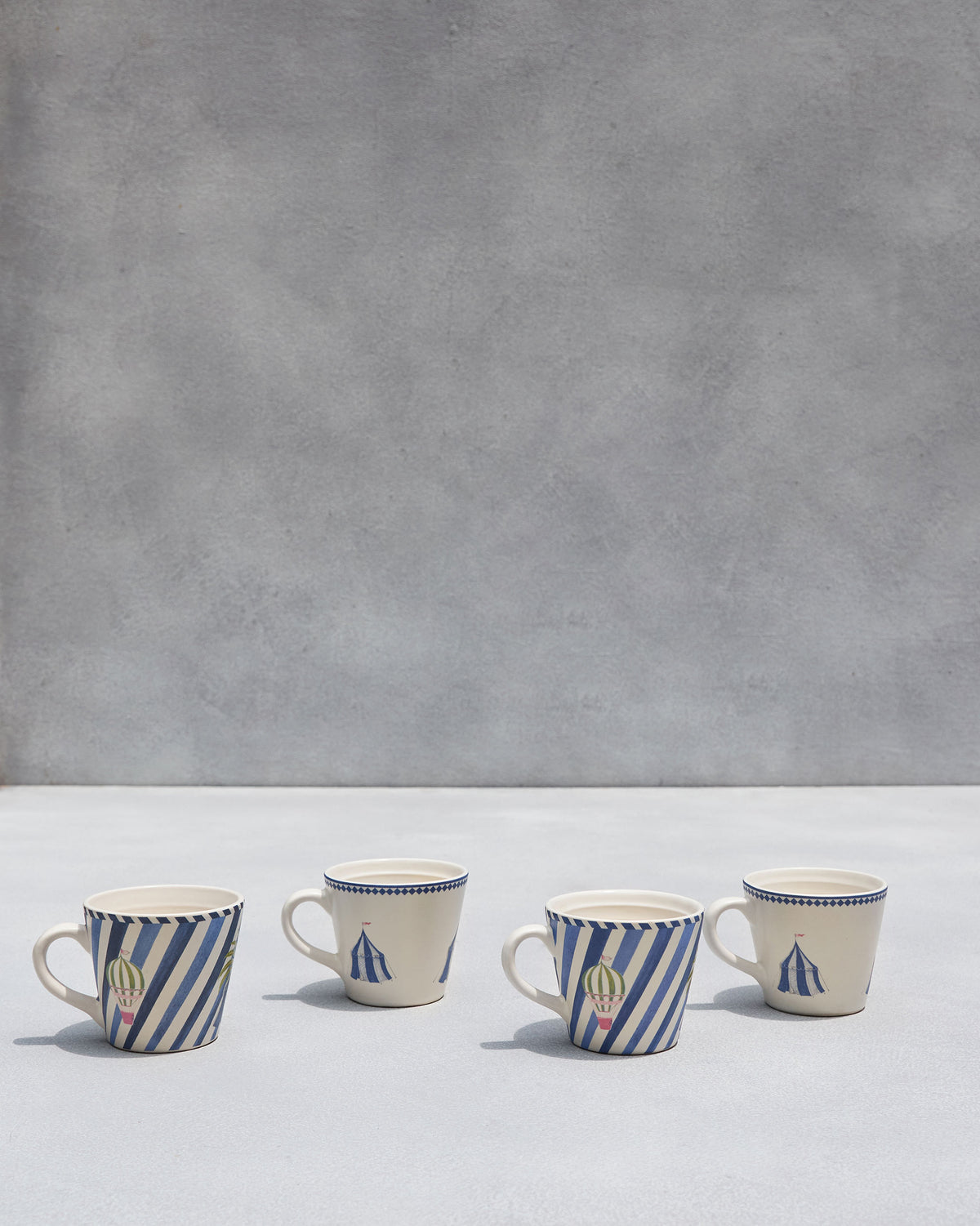 Sahara espresso mugs in cream tent and blue-striped balloon designs.