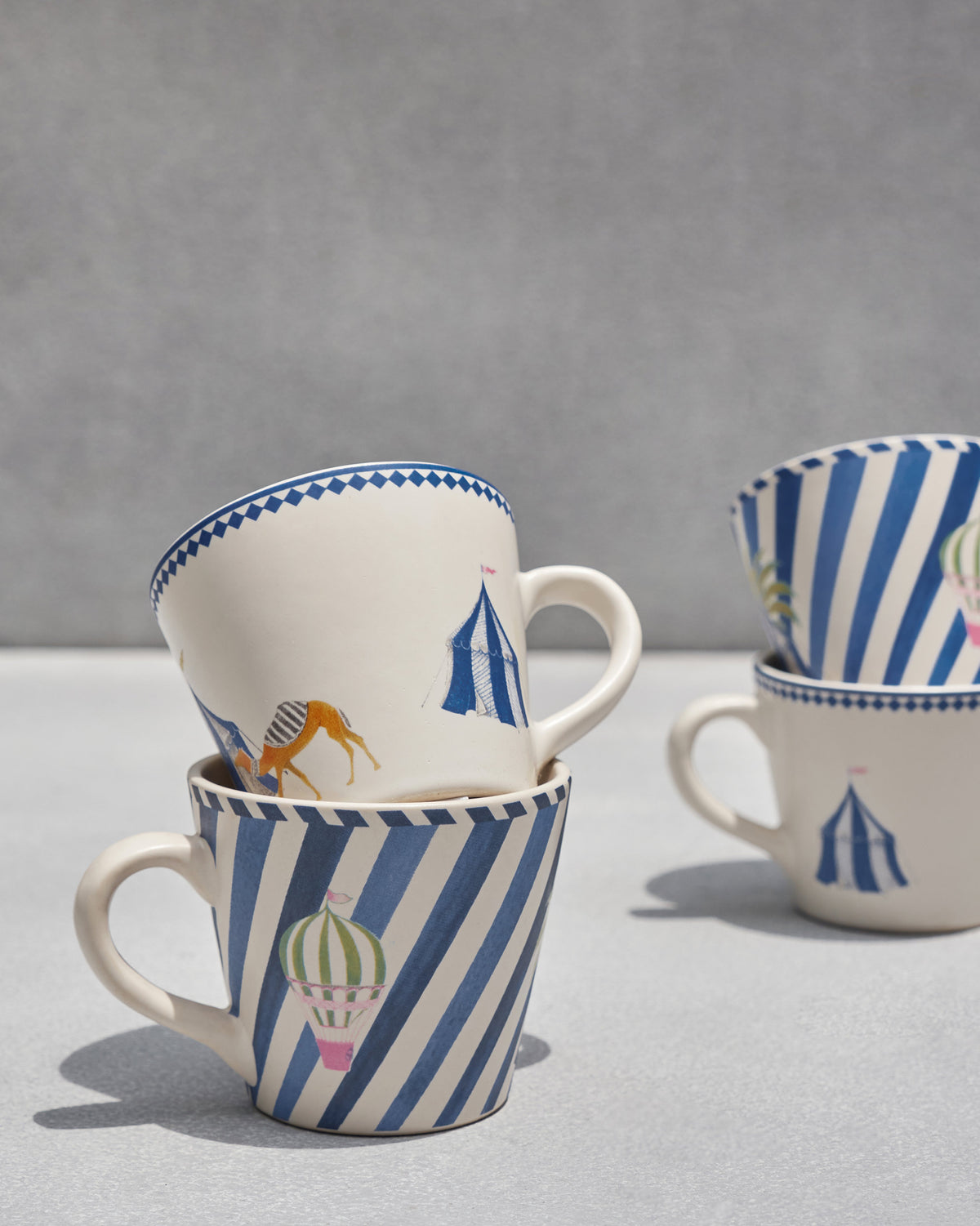 Sahara espresso mugs stacked showing camel and hot air balloon motifs.