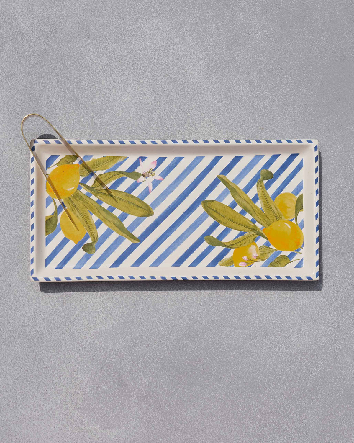 Overhead view of the Asfar lemon stripe cookie tray with gold tongs.