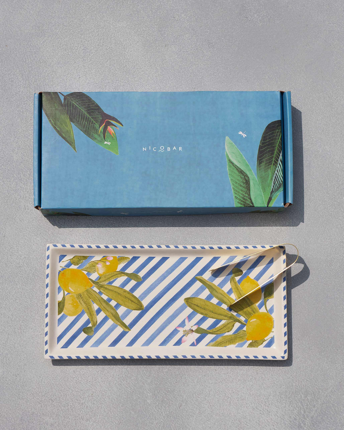 Asfar cookie tray with lemon motifs and gold tongs beside a blue Nicobar box.