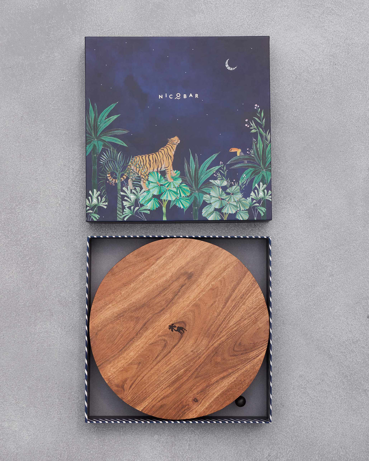 Round wooden board of the Sahara cheese board set inside its open box.