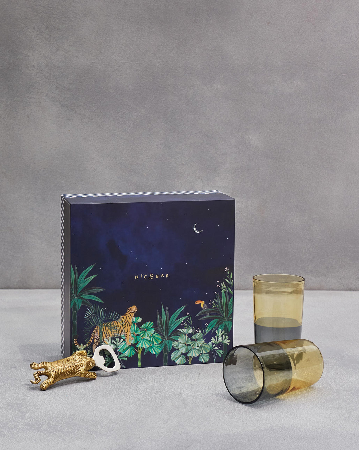Asfar gift set with amber-and-smoke tumblers and a gold tiger bottle opener.