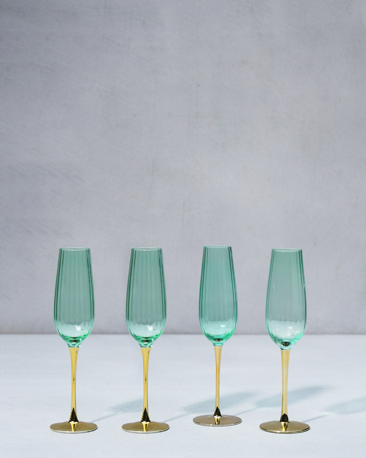 Four seafoam green champagne flutes lined up in a row.