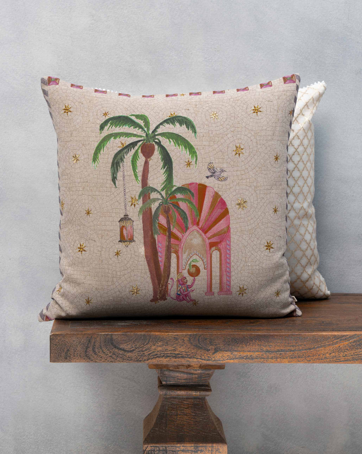 Chambray Arch Cushion with a pink arch, palm trees and gold stars.