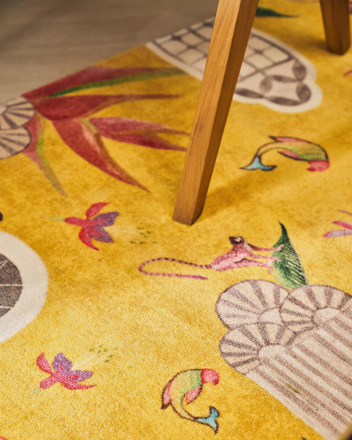 Angled close-up of the yellow Mandovi rug showing birds and flowers.