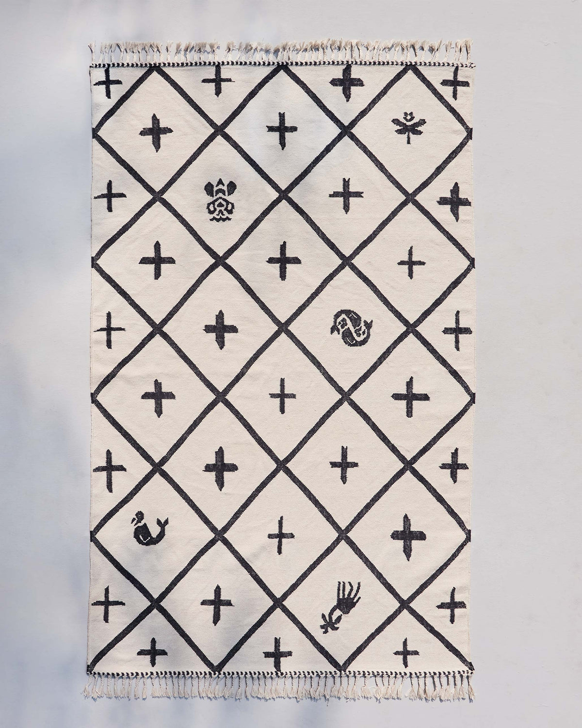Morocco tiles rug in cream with a black diamond lattice and cross motifs, laid flat.