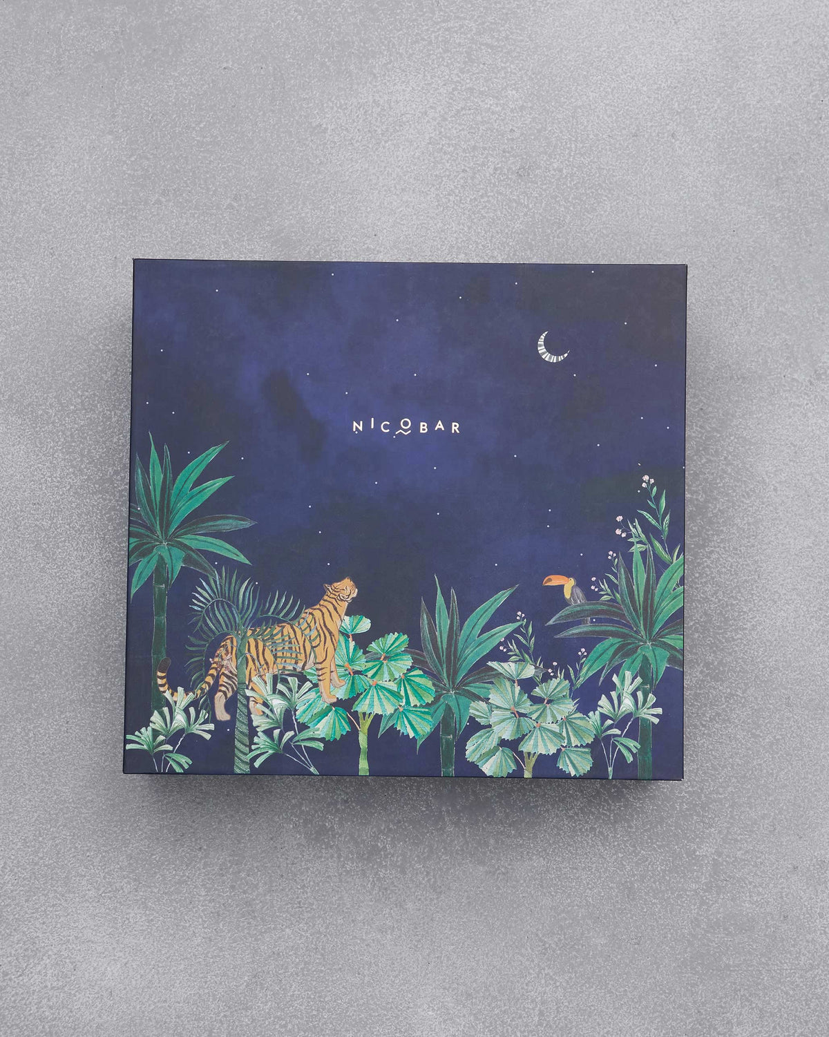 Navy Nicobar gift box with a tiger, toucan, and crescent moon jungle scene.